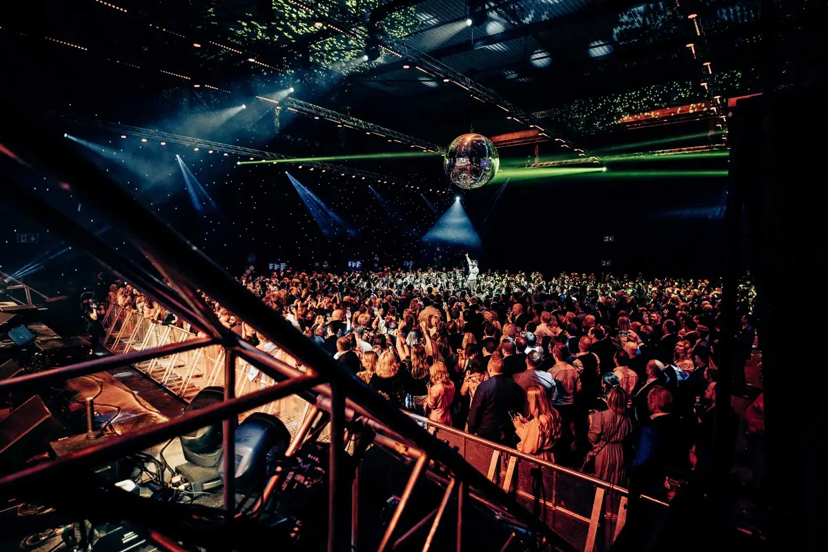 Packed dance floor under a disco ball and light show at TV 2's 30th anniversary in Kjødehallen